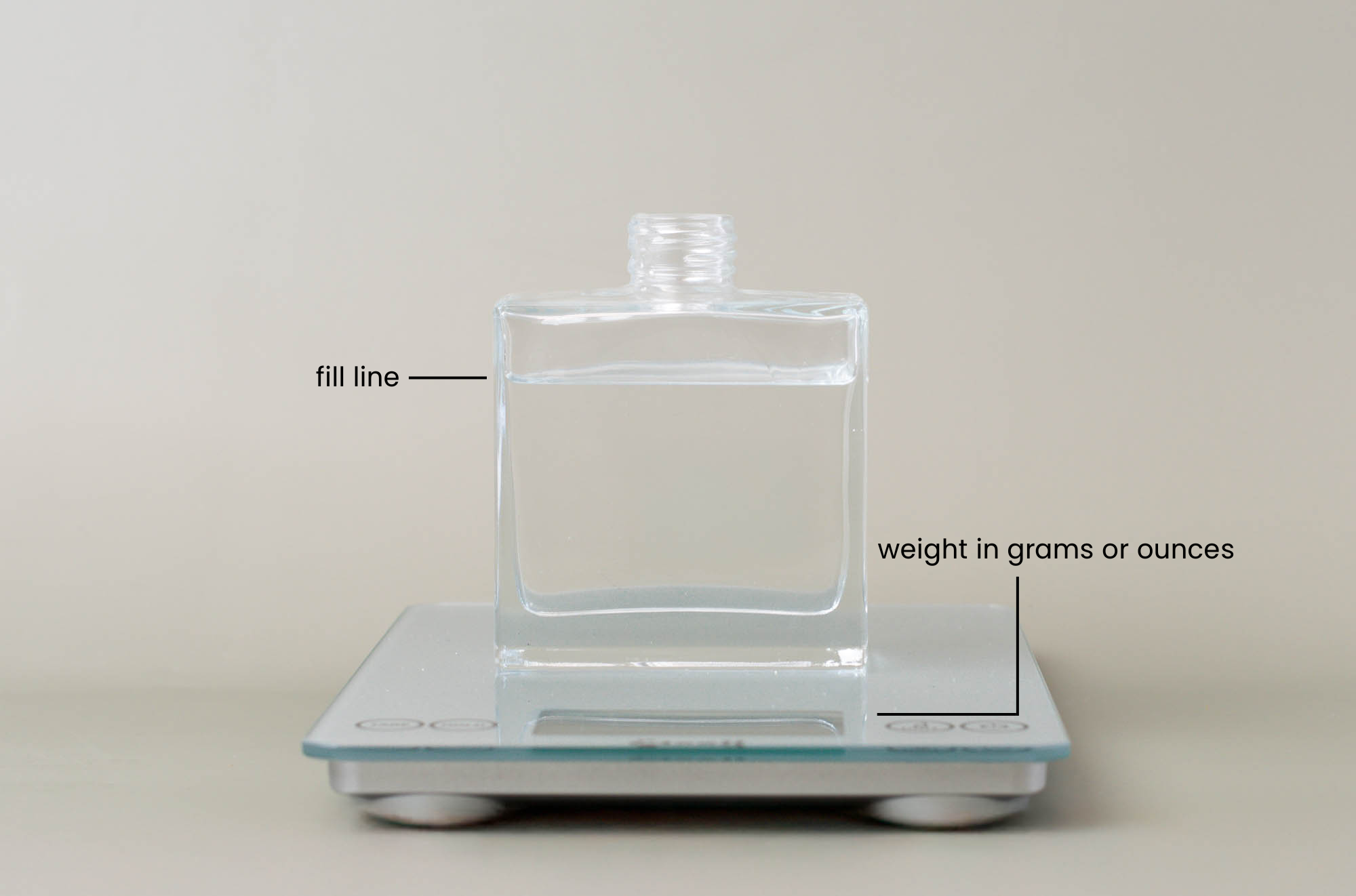 A full glass reed diffuser on a scale with lines indicating the fill line and weight. 